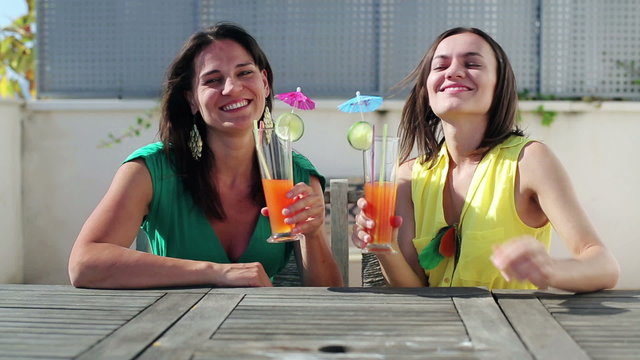 Female friends raising a toast with cocktails, outdoors