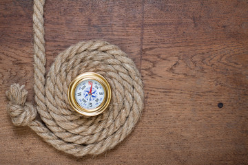 Compass and rope knot on the old wooden background