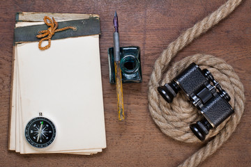 Old notebook, compass, ink pen, rope on the grunge wood