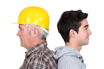 tradesman standing back to back with his apprentice