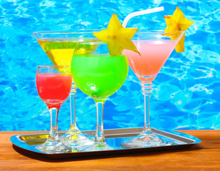 Glasses of cocktails on wooden table on blue sea background