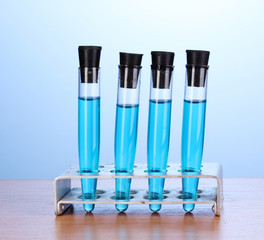Test-tubes with blue liquid on wooden table on blue background