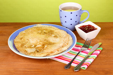 Stack of tasty pancakes on wooden table on green background
