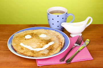 Stack of tasty pancakes on wooden table on green background