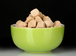 brown cane sugar cubes in bowl on black background