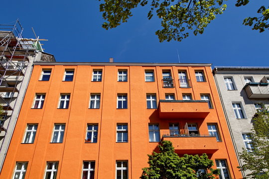 Façade orange avec balcons et ciel bleu.
