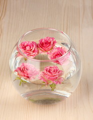 Vase with roses on wooden background