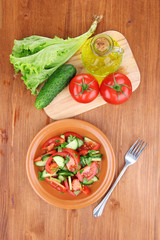 Fresh salad with tomatoes and cucumbers on wooden background