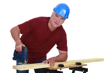Grey-haired carpenter using electric saw