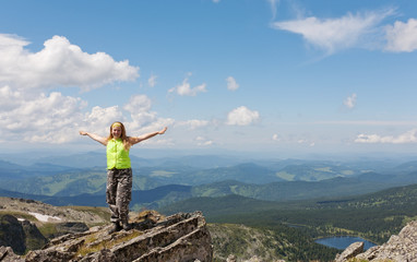 Fototapeta premium girl tourist to stand on rock, having stretched hands