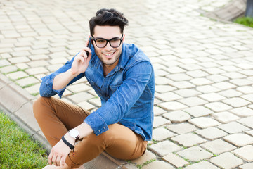 handsome young man talking on a smartphone outdoors