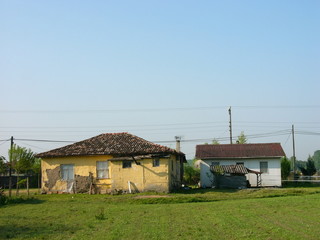 Fassade in Beige und Ocker eines alten Haus mit traditionellem Ziegeldach vor blauem Himmel im...