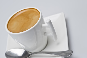 Café cremoso en una taza con platillo cuadrado.