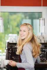 lächelnde verkäuferin an der kaffeemaschine