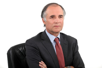 Senior businessman sat with his arms crossed