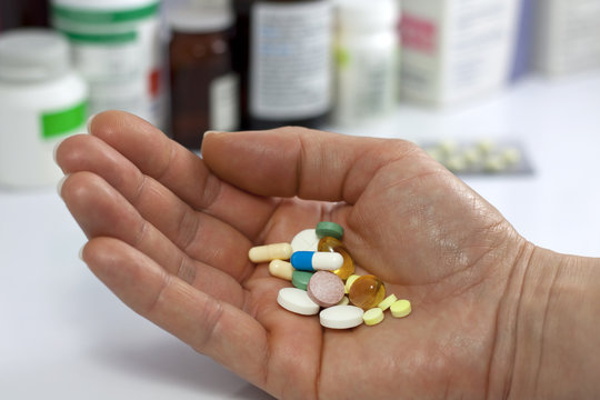pills in hand against pharmacy