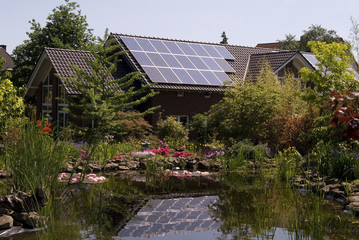 Haus mit Solarzellen und Teich