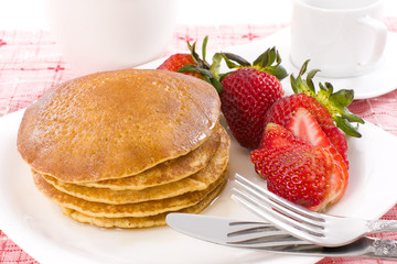 Pancake and strawberry have maple syrup on top with coffee