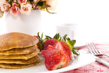 Pancake and strawberry have maple syrup on top with coffee