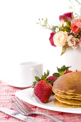 Pancake and strawberry have maple syrup on top with coffee