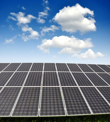 Solar energy panels against blue sky with clouds