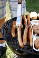 goldbraunes Grillwürstchen wird auf Grill gewendet