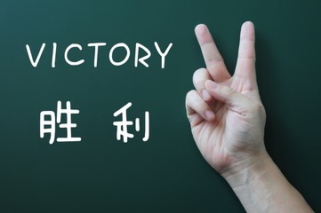 Victory gesture on a blackboard background