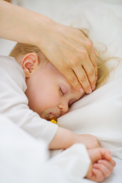 Closeup On Mother Checking Temperature Of Forehead Of Baby