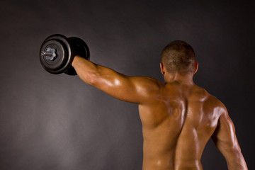Fototapeta na wymiar Muscled male bodybuilder dumbbell swing