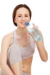 A sportive  girl sitting on the floor with a bottle of water