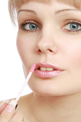 A young woman putting lipstick, closeup