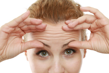 A young woman checking wrinkles on her forehead, closeup