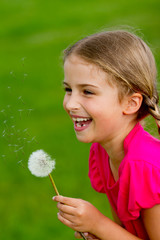 Summer joy - lovely girl blowing dandelion