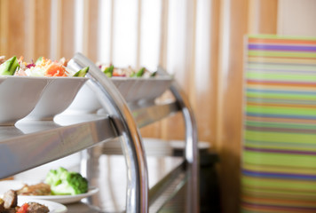 Hot trays with cooked food close-up in dining room