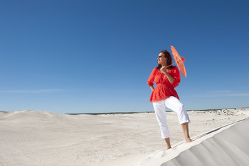 Attractive woman with umbrella on desert sand dune