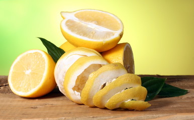 ripe lemons with leaves on wooden table on green background