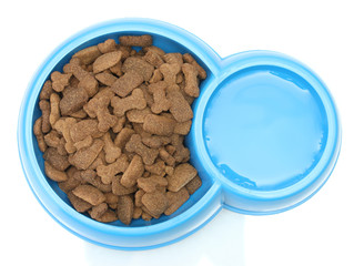 dry dog food and water in blue bowl isolated on white