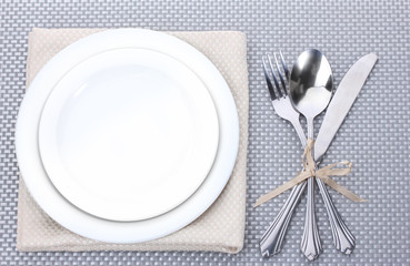 White empty plates with fork, spoon and knife tied with a