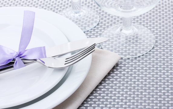 White empty plates, fork and knife tied with a ribbon and