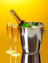 Champagne bottle in bucket with ice and glasses of champagne,