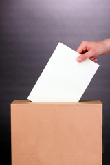 Obraz premium Hand with voting ballot and box on grey background