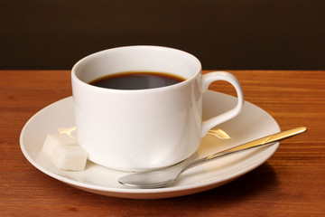 Coffee cup on wooden table on brown background