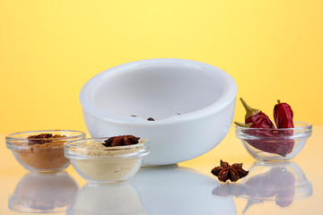White mortar and pestle with spice on yellow background