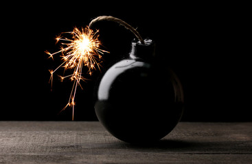 Cartoon style bomb on wooden table on black background