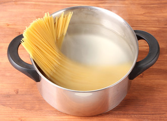 Cook the spagetti in the pan on wooden background close-up