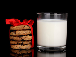 Glass of milk and cookies isolated on black