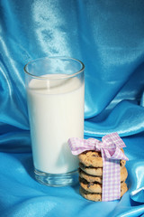 Glass of milk and cookies on blue cloth background
