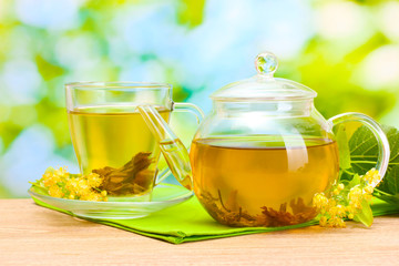 teapot and cup with linden tea and flowers