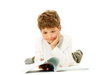 A boy lying on the floor and reading a book, isolated on white