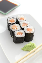 Salmon Maki sushi with chopsticks and soy sauce in white backgro